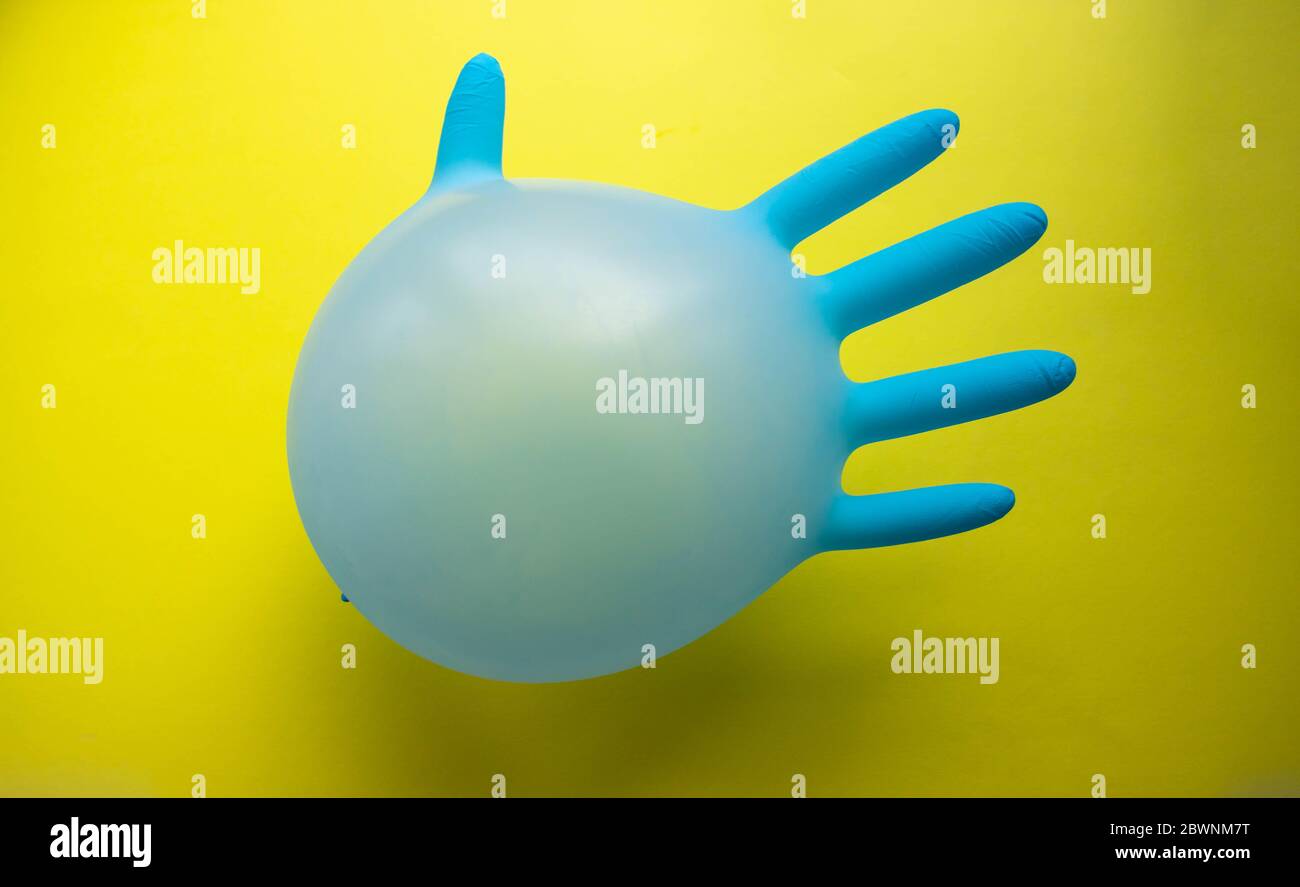 Flying blue rubber surgical glove in the form of a balloon on a yellow