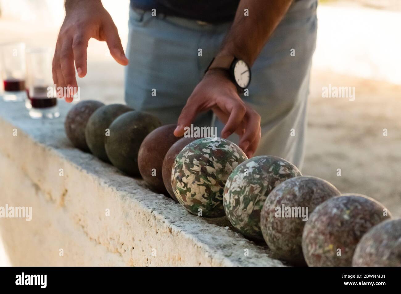 A man's hand grabs a stone lawn bowling ball Stock Photo