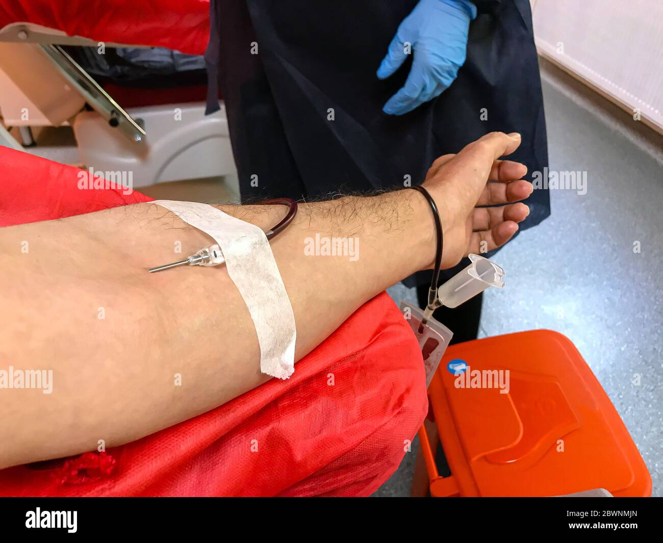 Blood donor at donation, transfusion. Close up right arm of a business man receiving blood in hospital. Healthcare and charity. Also concept image bac Stock Photo