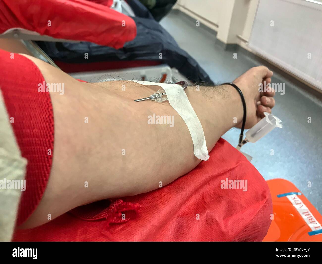 Blood donor at donation, transfusion. Close up right arm of a business man receiving blood in hospital. Healthcare and charity. Also concept image bac Stock Photo