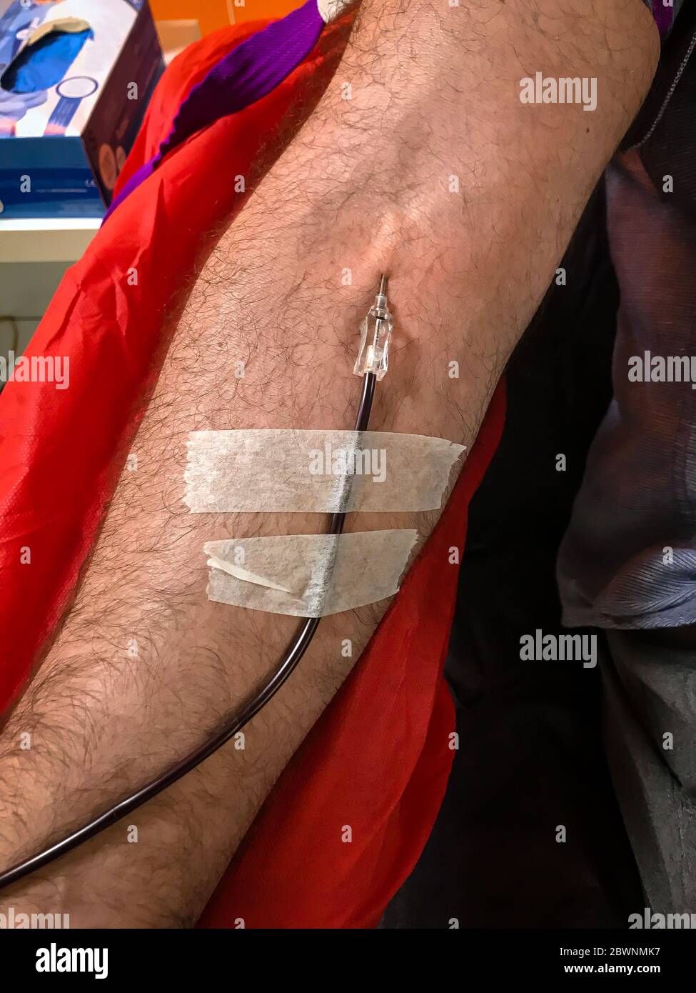 Blood donor at donation, transfusion. Close up right arm of a business man receiving blood in hospital. Healthcare and charity. Also concept image bac Stock Photo