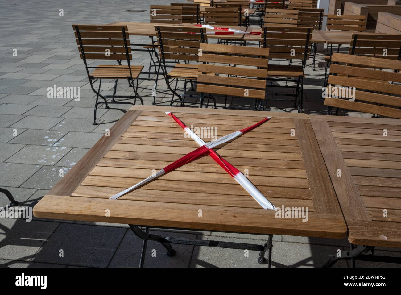 Locked table with red and white flutter band in a street cafe during the coronavirus crisis, keeping the prescribed social distance to reduce the risk Stock Photo