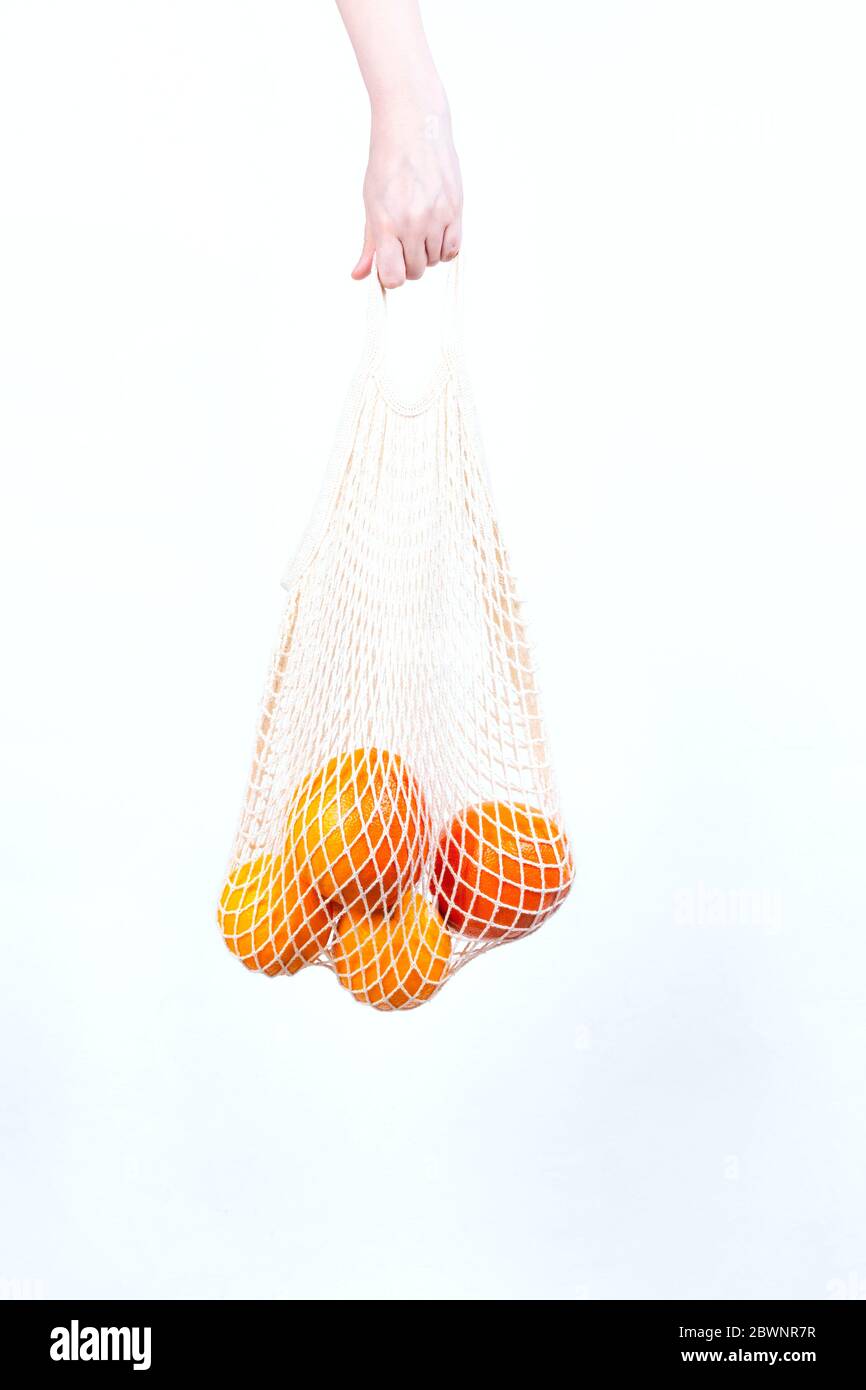 Woman's hand is on hold string bag with oranges and grapefruits. Concept zero waste, eco-friendly Stock Photo