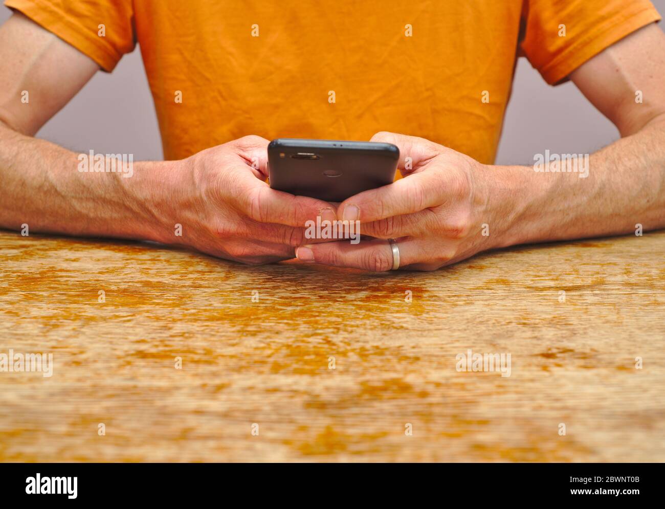 Mid section of man holding smartphone in both hands Stock Photo