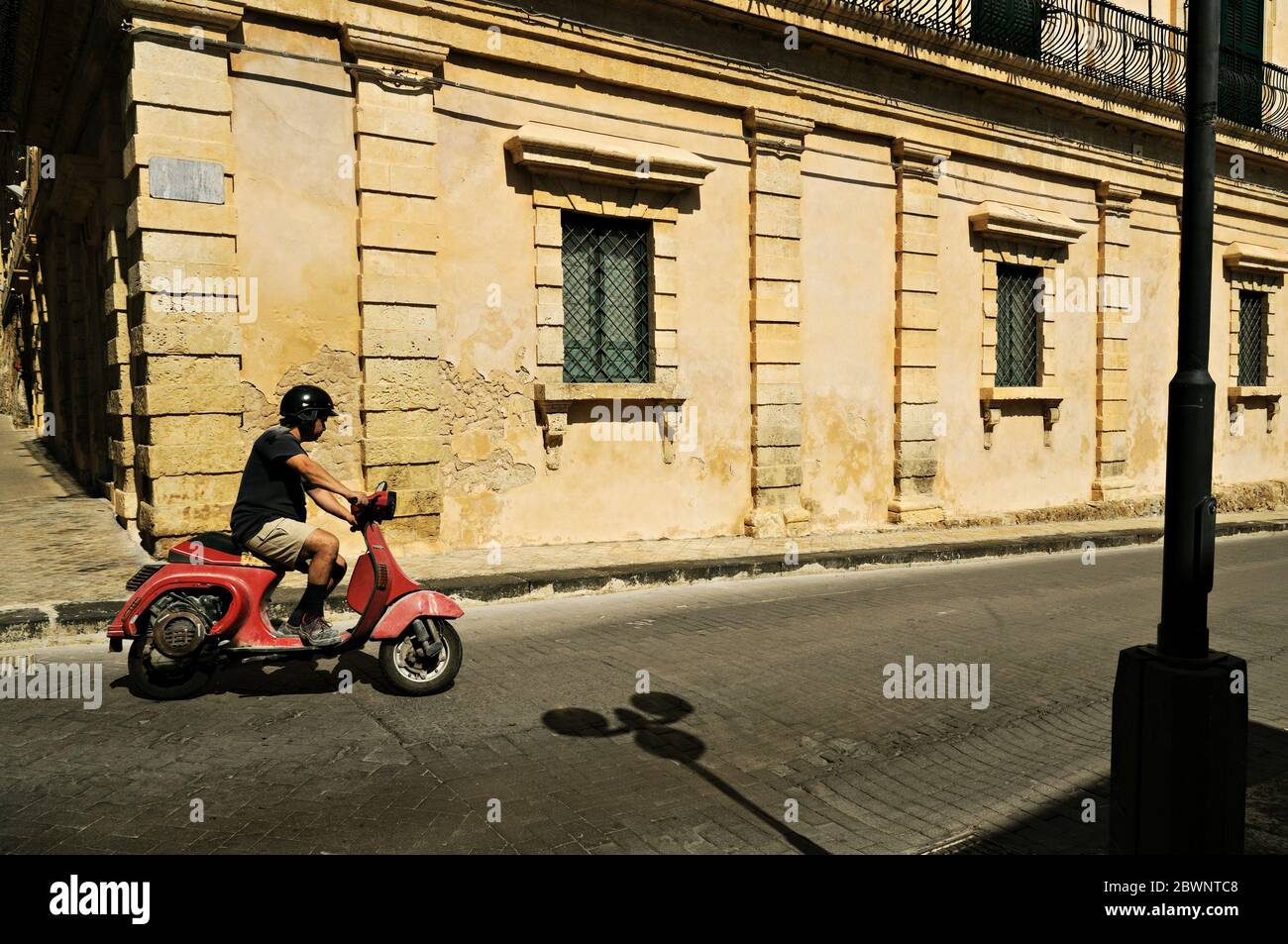 Man on a red vespa in Noto, Sicily, Italy Stock Photo