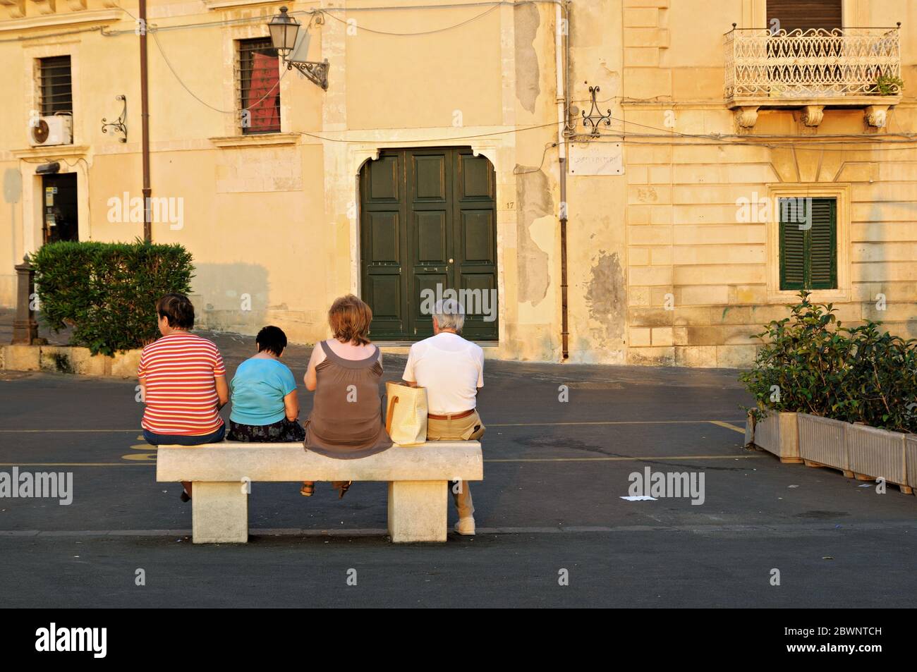 Elderly people sit on public bench in Syracuse, Sicily, Italy Stock Photo