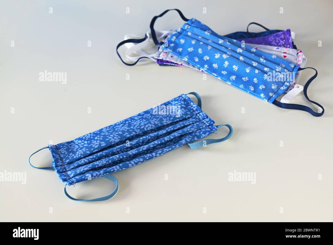 Sustainable washable masks for multiple use, homemade sewn from blue patterned cotton as protection against coronavirus pandemic on a gray background, Stock Photo