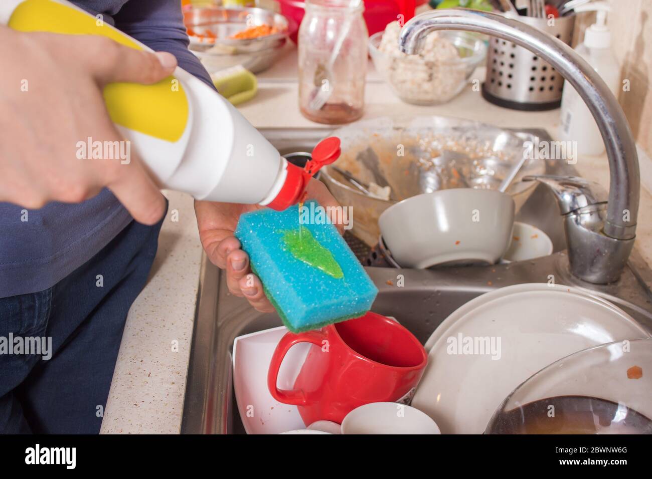 A woman's hand holds a dishwashing sponge onto which a dishwashing