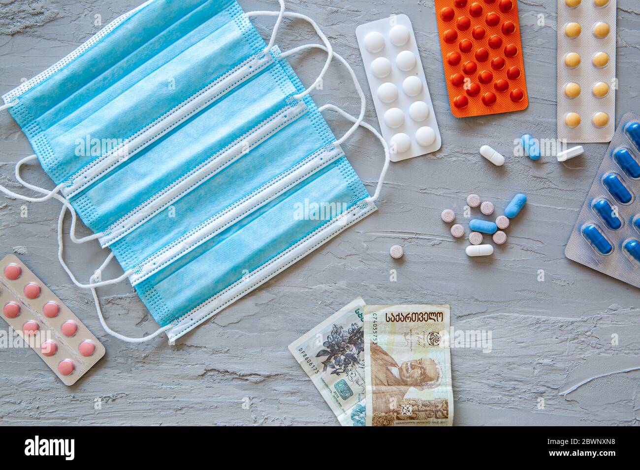 Medical and health costs during coronavirus crisis. Epidemic covid-19 concept in Georgia. Georgian banknotes, masks and pills. Stock Photo