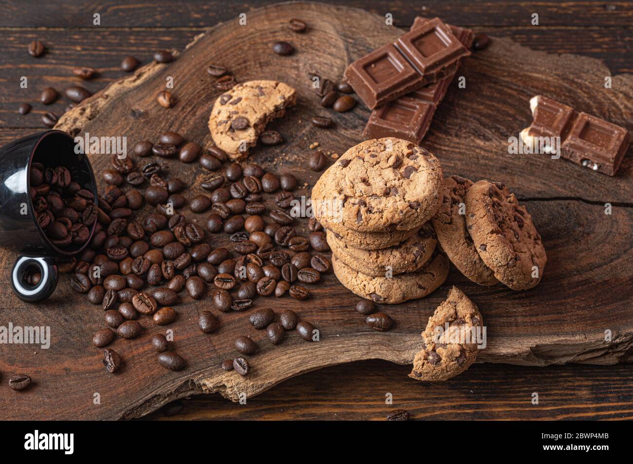 Cookies, pieces of chocolate and coffe beans over a wooden board Stock Photo