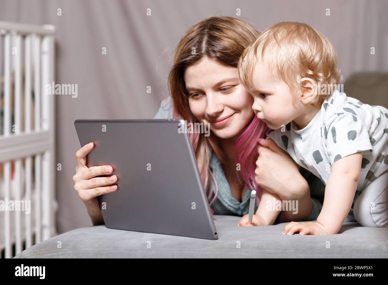 Stay at home, mom works remotely on a laptop computer, taking care of her child. A young mother on maternity leave is trying to work as a freelancer w Stock Photo