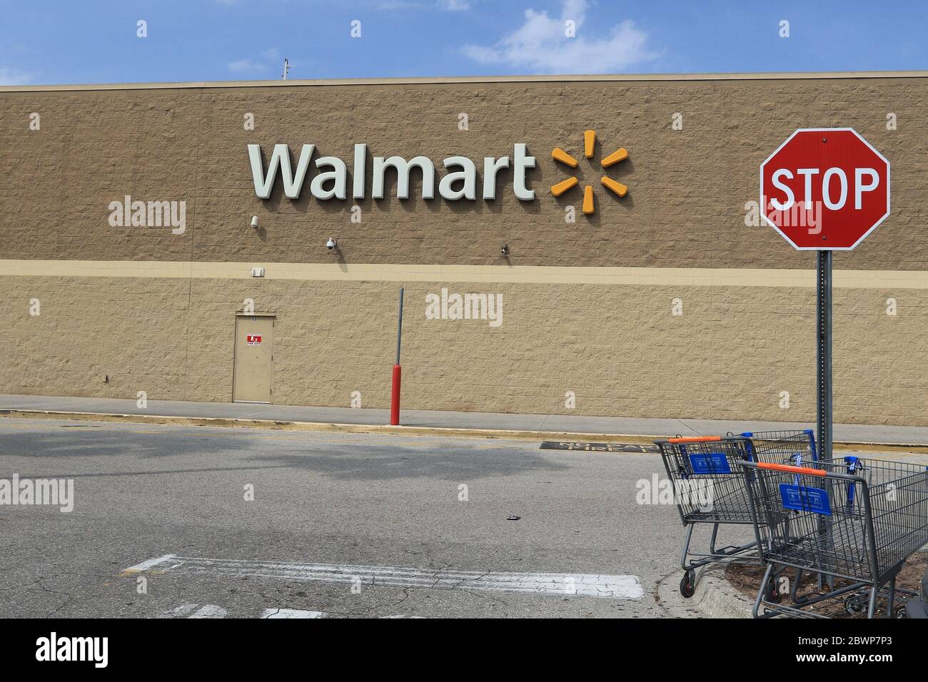 Bradenton, FL, 4/17/2020: View of an external wall of a Walmart store. A couple of shopping carts are left next to a stop sign on the parking lot. Stock Photo