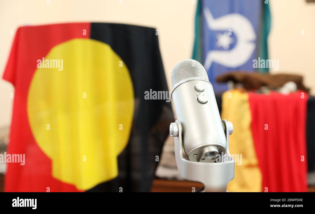 Simple image of a microphone radio device with a backdrop of the australian indigenous aboriginal flag and torres strait island flag blurred in the ba Stock Photo