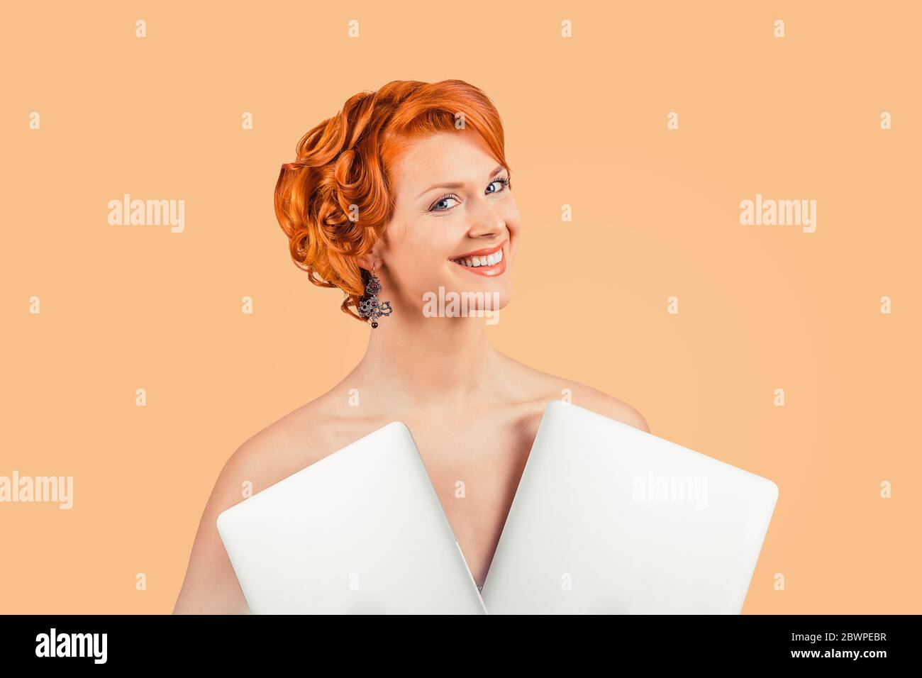 Girl with two laptops as a dress. Closeup red head beautiful young woman happy pinup girl in dress made of laptops computers, with curly updo retro vi Stock Photo