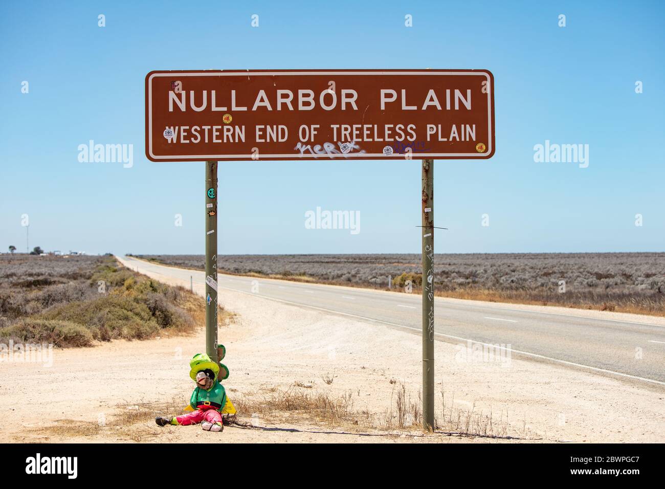 Nullarbor Plian Australia November 16th 2019 : Leprachaun doll seated at the base of the famous Nullarbor Plain sign in Western Australia Stock Photo