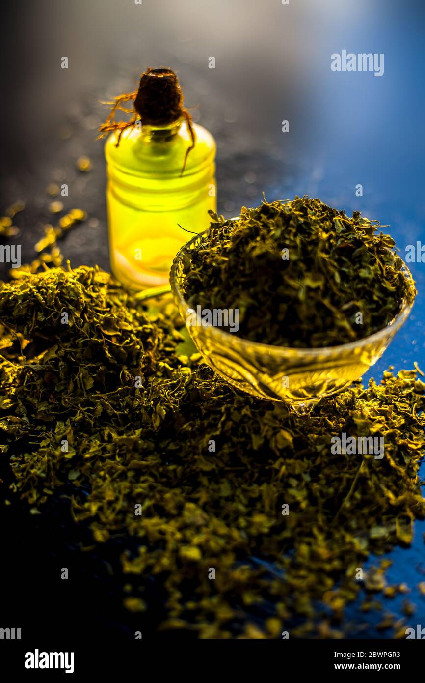 Shot of essential oil of Kasuri Methi or Dried Fenugreek in a glass bottle along with some dried powder fenugreek in a bowl. Stock Photo