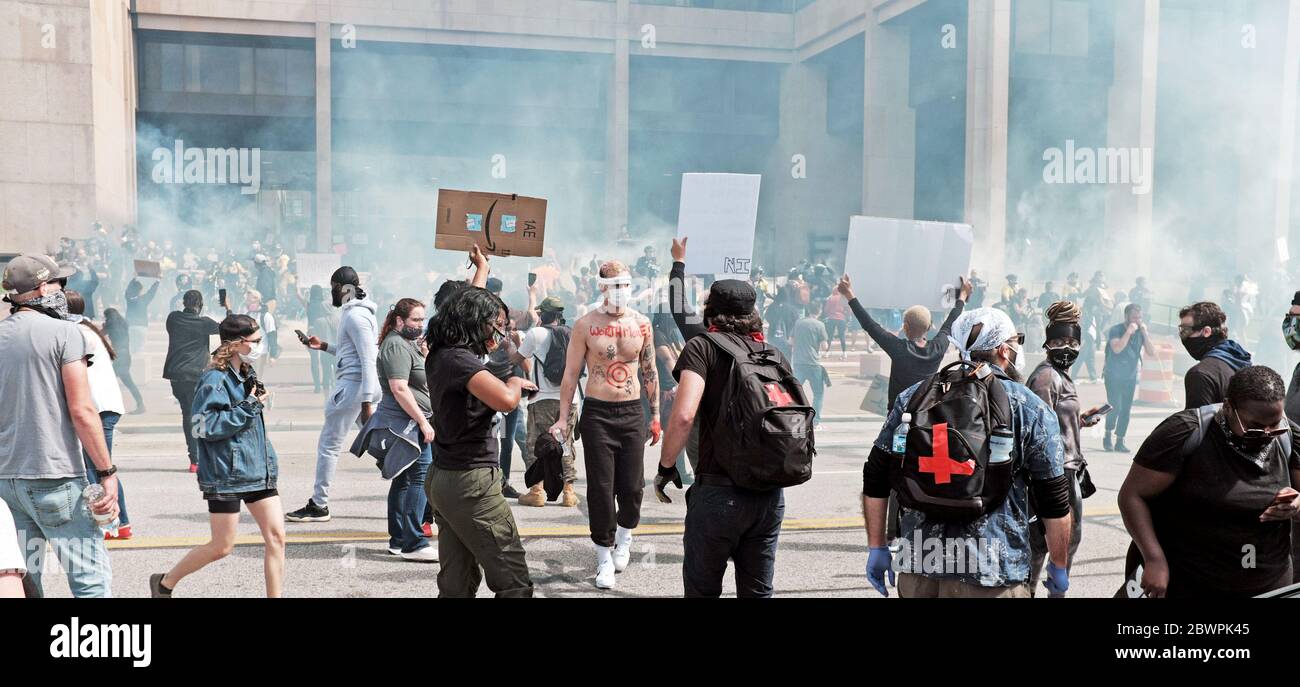 Cleveland, Ohio, USA.  30th May, 2020. A white man walks through a diverse crowd of protesters being tear gassed by the Cleveland police during the George Floyd demonstrations in Cleveland, Ohio, USA.  Thousands of protesters marched to the Justice Center on Lakeside Avenue where protests turned violent before spreading throughout downtown.  Black Lives Matter, social justice, and reform of police culture are many of the issues culminating in the protest.  Cleveland is one of many cities across the United States, and around the world, protesting against police brutality in the United States. Stock Photo