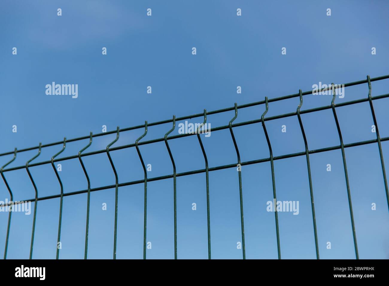 Steel grill fence with wire against the blue sky. Stock Photo