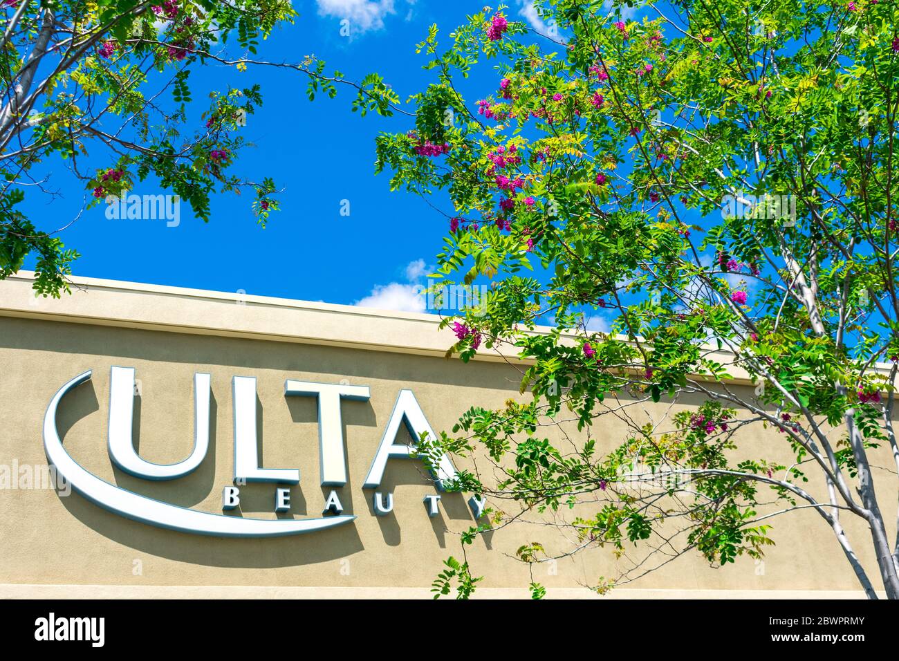 Ulta Beauty sign on chain store facade behind blooming green trees