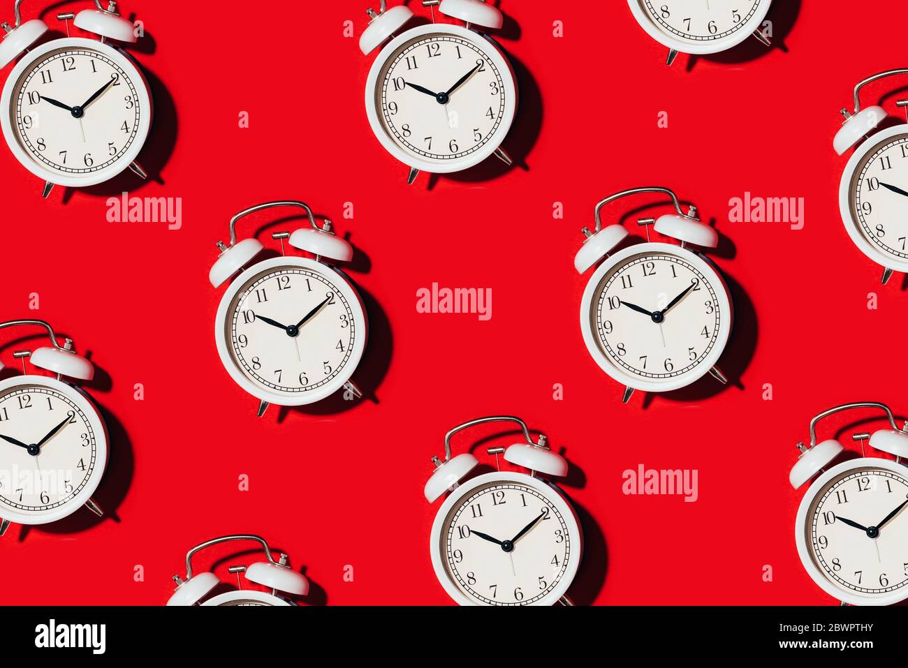 Pattern of white alarm clock on red background. Wake up alert concept