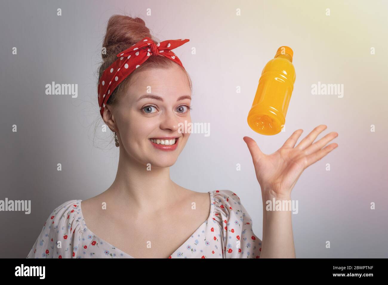 Smiling young caucasian woman girl  holding advertising a bottle of orange or mango fruit juice Stock Photo