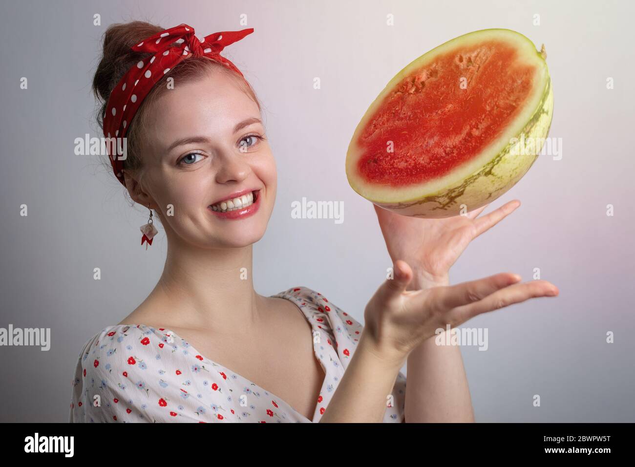 Smiling young Caucasian woman girl  holding advertising a watermelon cut in half.Vegetarian lifestyle or summer vibes concept Stock Photo