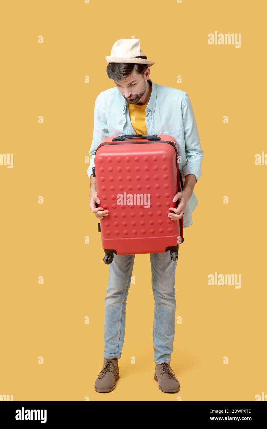 Sad man clutching a suitcase looking down Stock Photo