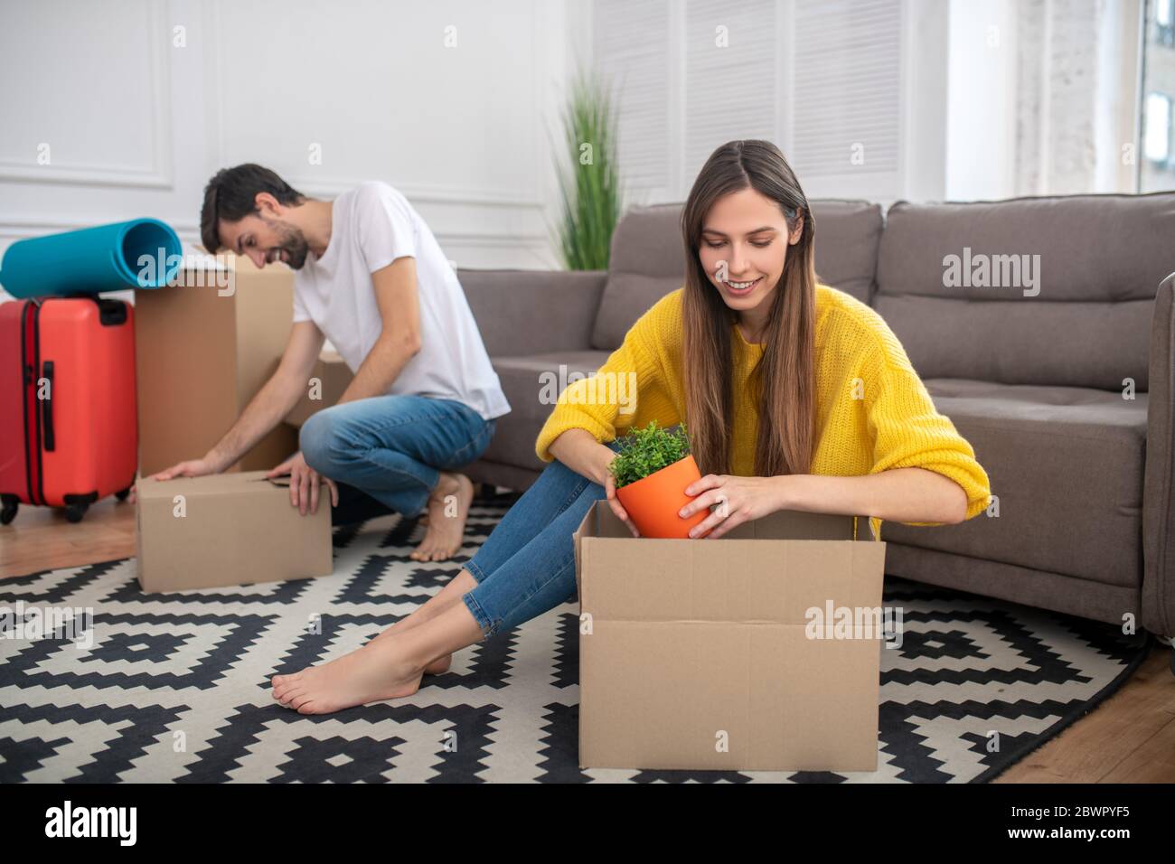 Girl sitting with flowerpot in the hands, man closing box Stock Photo