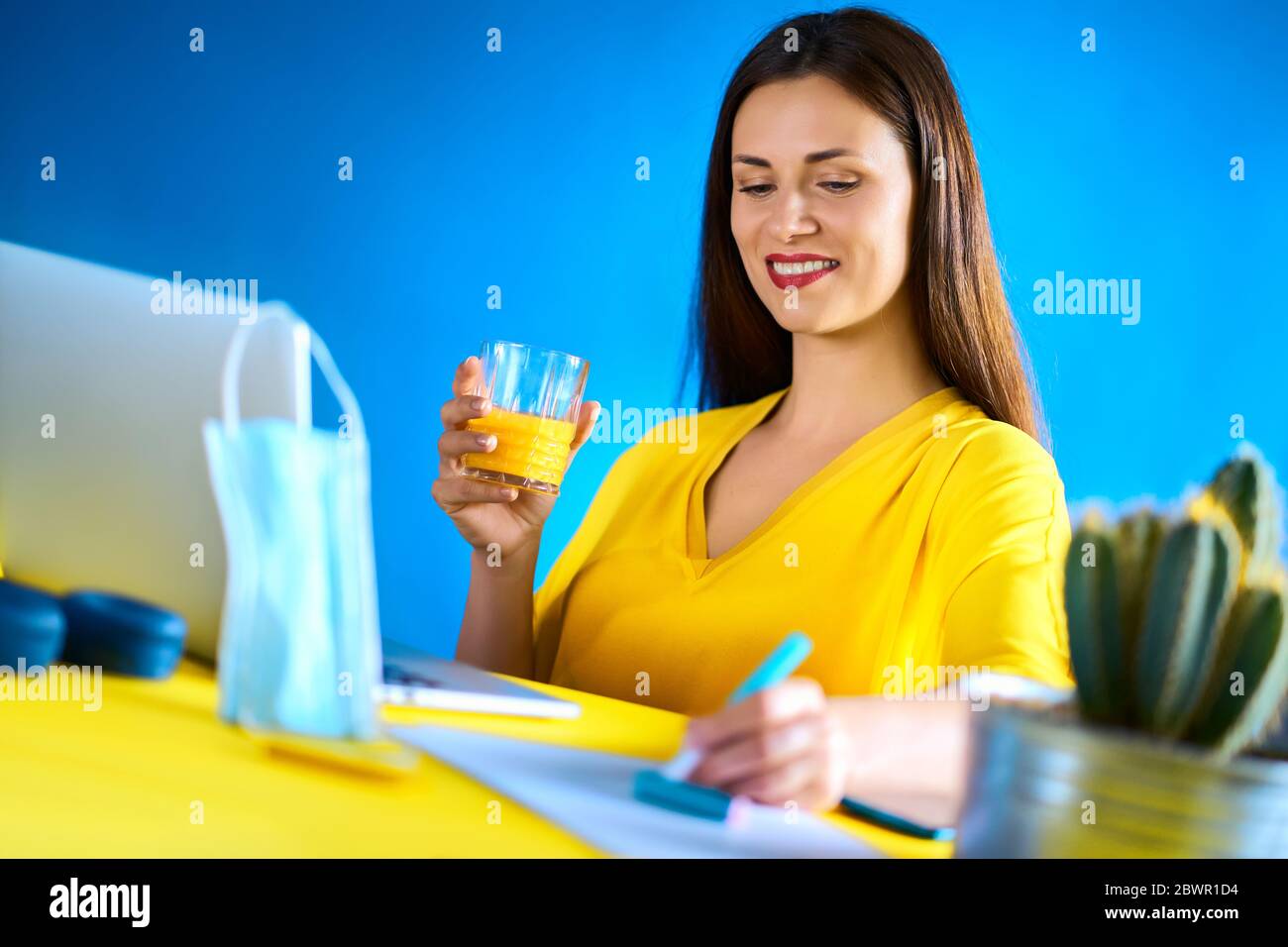 woman drinks juice and works during quarantine Stock Photo