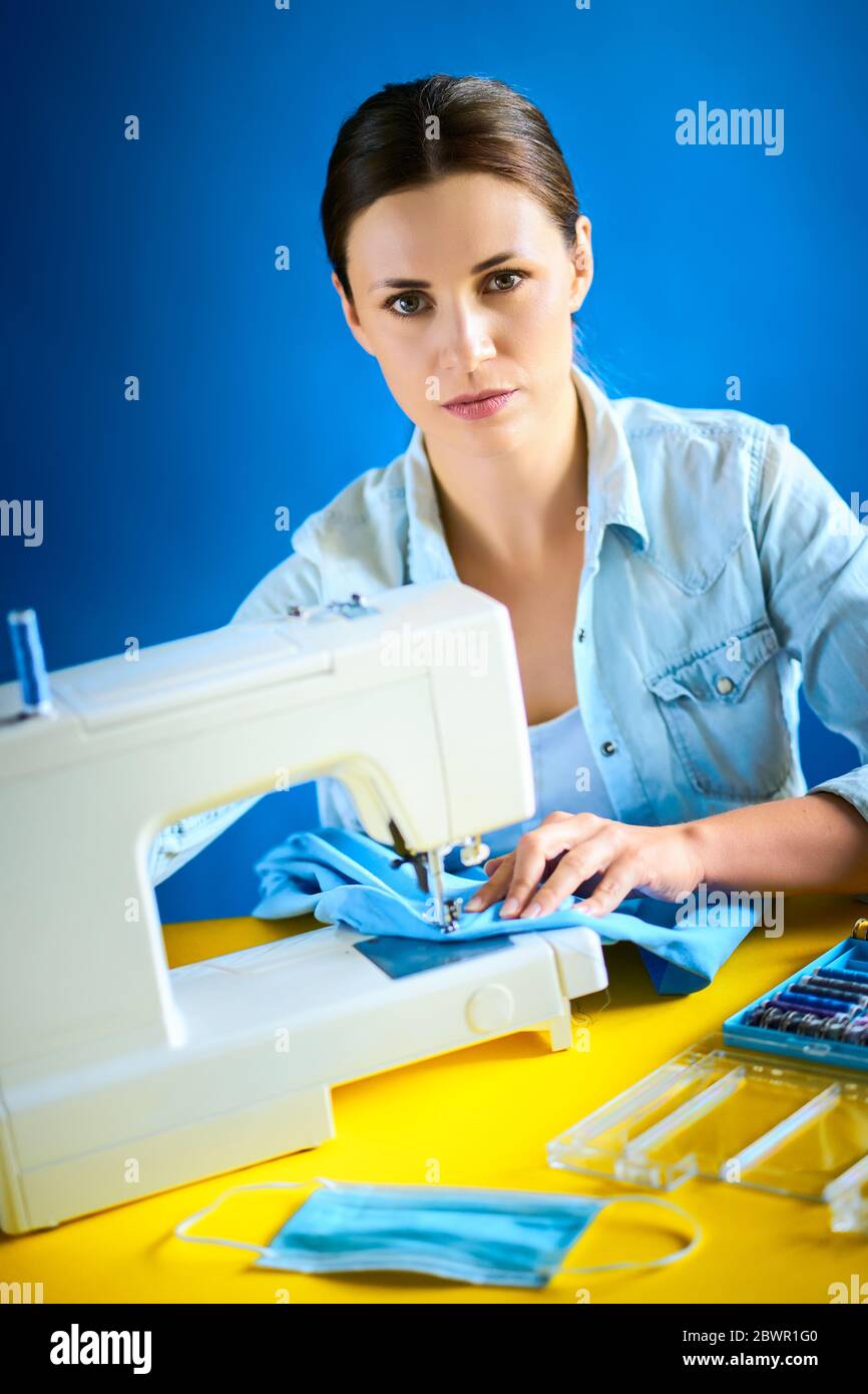 woman sews masks on the machine during quarantine Stock Photo
