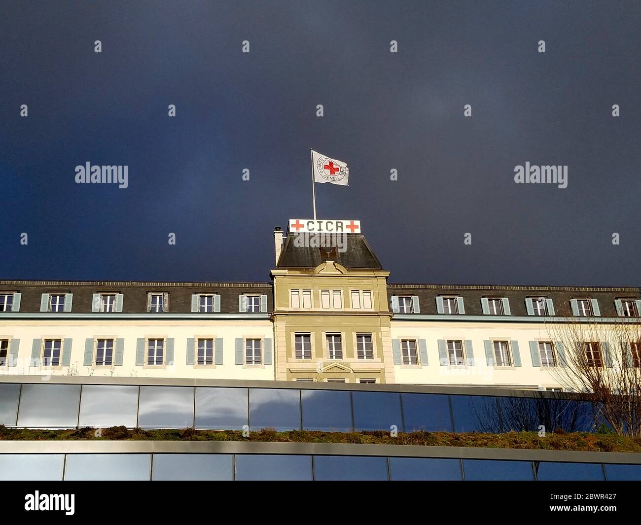 Dark storm clouds approaching the headquarters of the International Committee of the Red Cross, ICRC, with the Red Cross flag, Geneva, Switzerland. Stock Photo