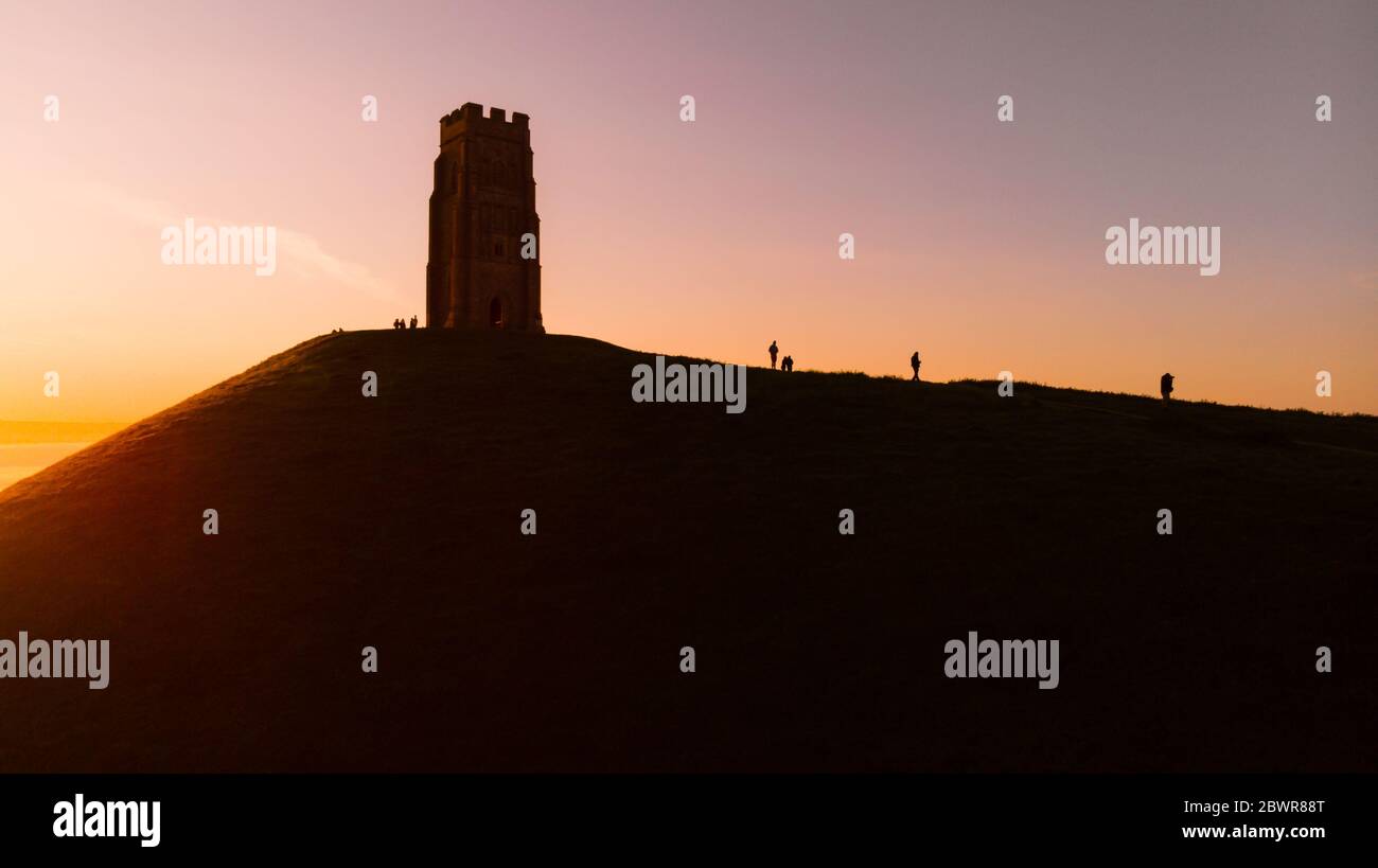 Early morning sunrise over Glastonbury Tor with silhouettes of people, Somerset. Stock Photo