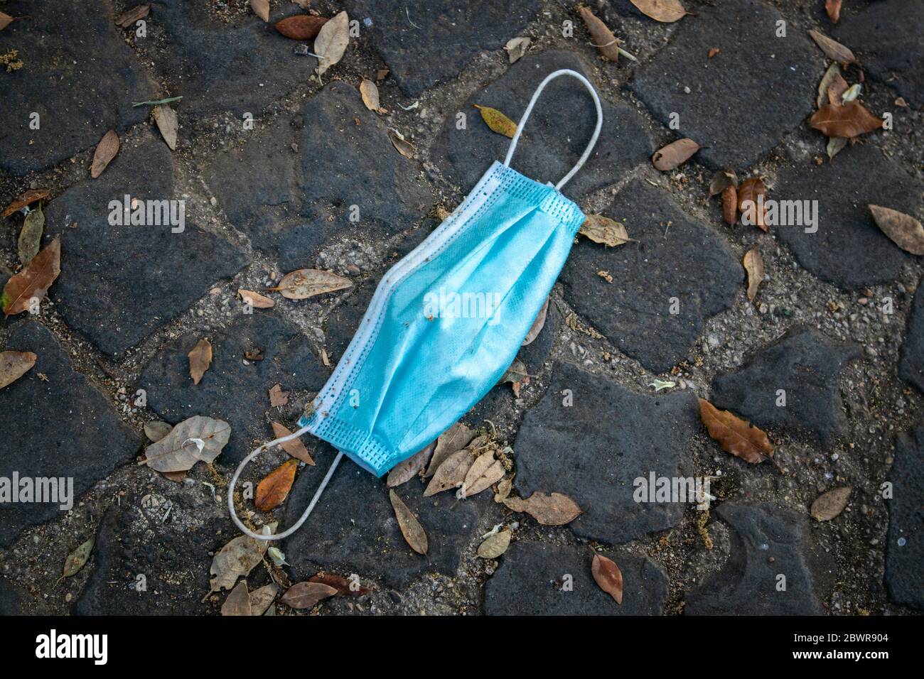 A protective mask abandoned on the road, on the ground. Symbol of the end of the restrictions for the coronavirus pandemic. Stock Photo