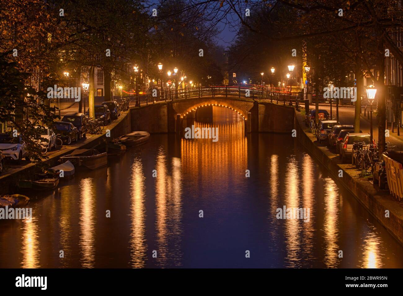 Reflections of bridge lighting in canals at dusk, Amsterdam, North Holland, Netherlands. Stock Photo
