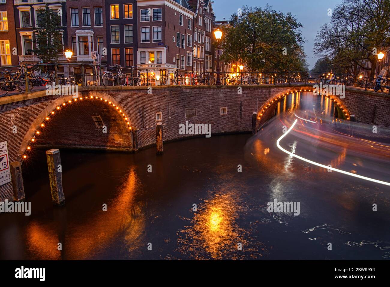 Reflections of bridge lighting in canals at dusk, Amsterdam, North Holland, Netherlands. Stock Photo
