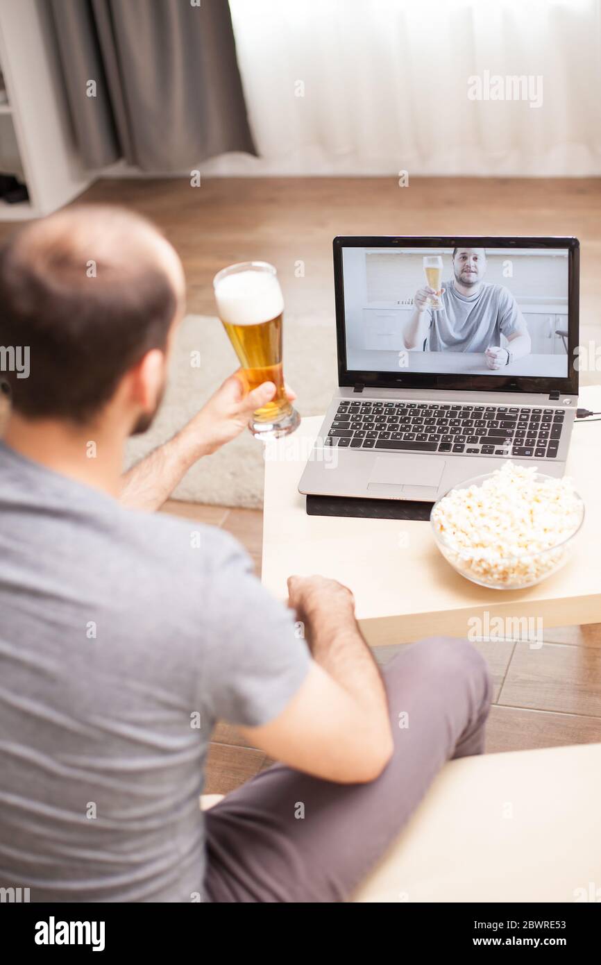 Friends talking on video call and drinking beer during social ...