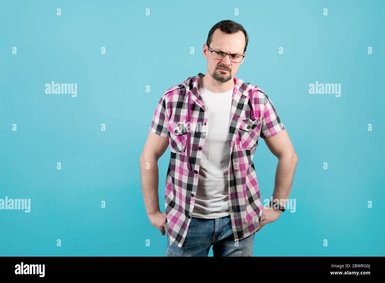 Puzzled man in a plaid shirt, glasses with bristles looks away Stock Photo