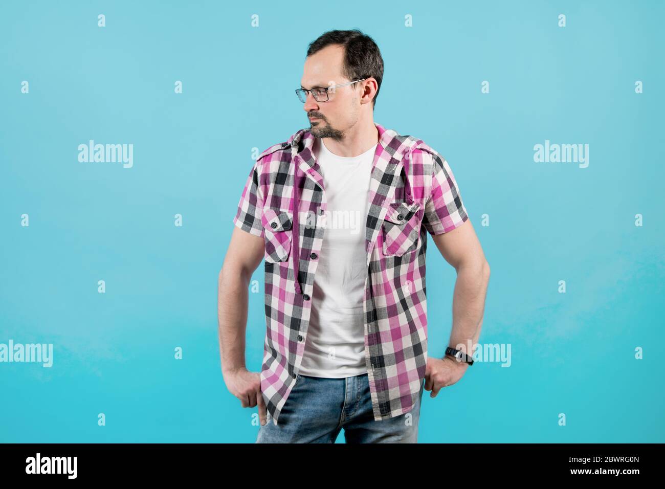 Puzzled man in a plaid shirt, glasses with bristles looks away Stock Photo