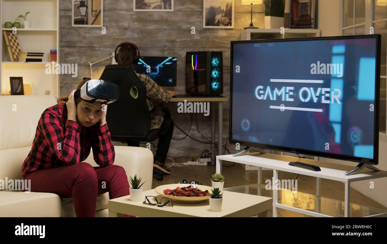 Woman experiencing virtual reality while playing video games using vr headset. Game over for female gamer. Stock Photo