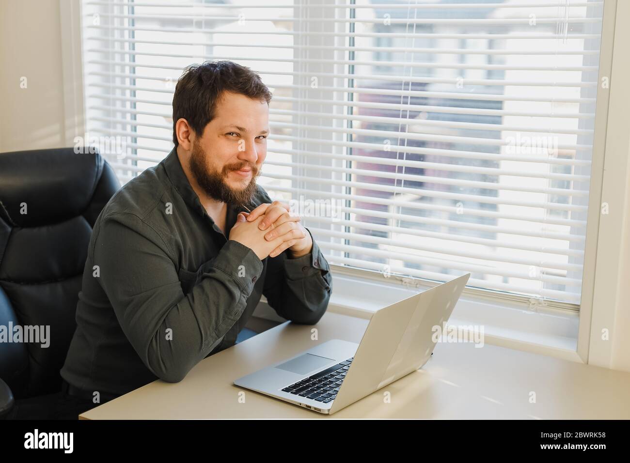 Smiling computer hacker working online with laptop at cabinet. Stock Photo