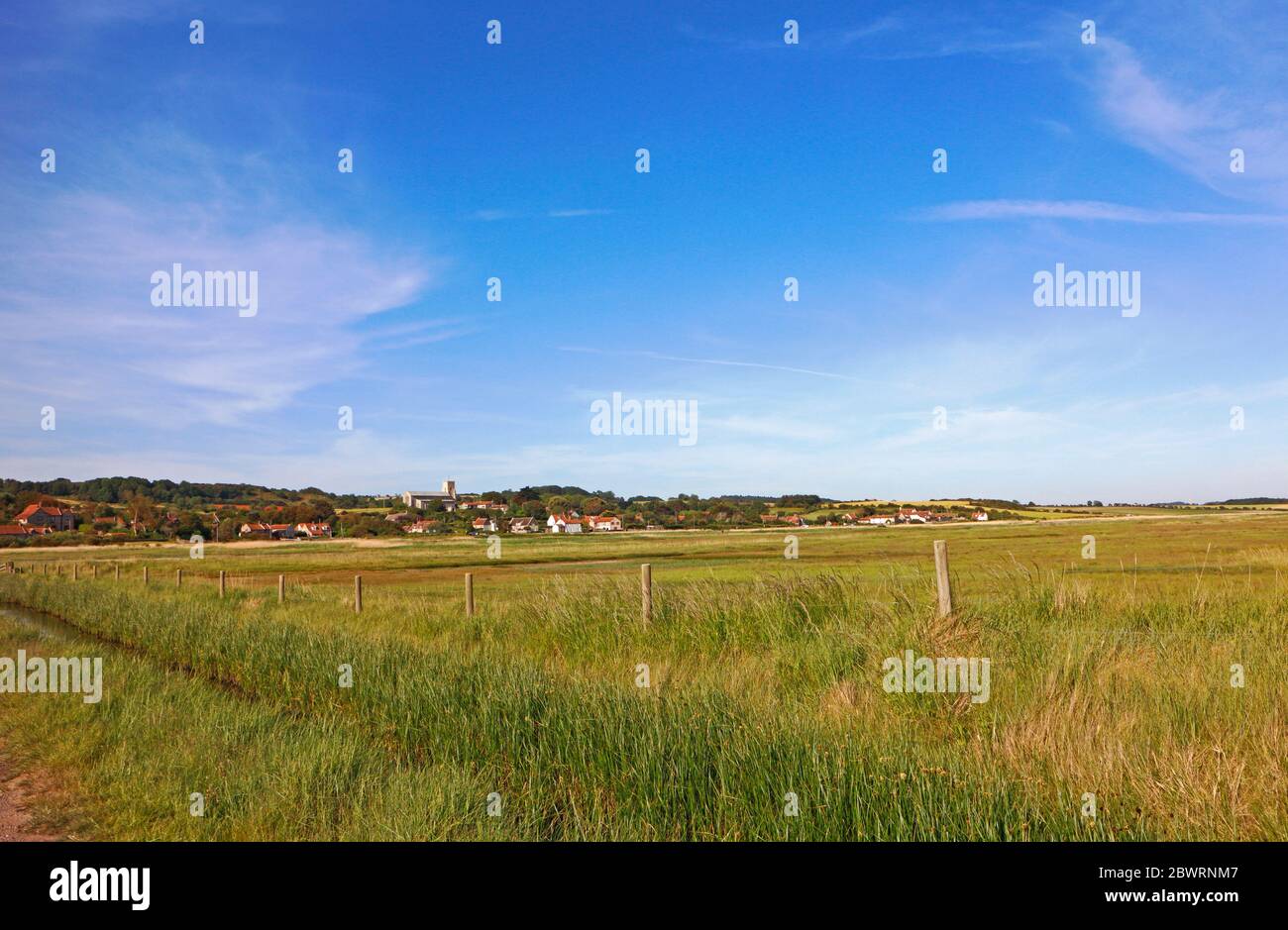 A view across the marshes from Beach Road on the North Norfolk coast to the village of Salthouse, Norfolk, England, United Kingdom, Europe. Stock Photo