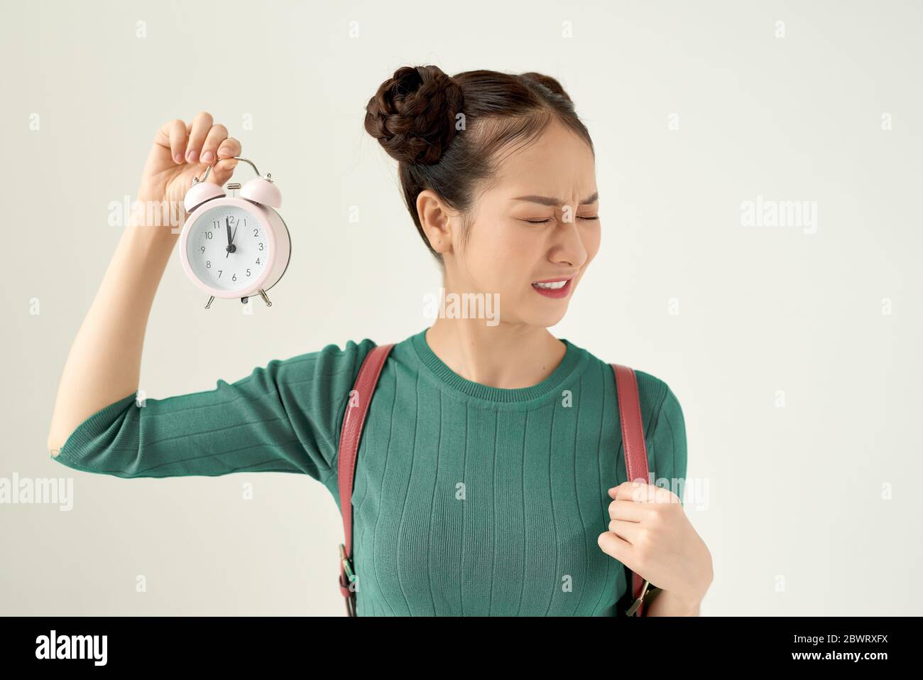 Young asian woman feeling confused and uncertain, doubting with puzzled look holding a clock Stock Photo