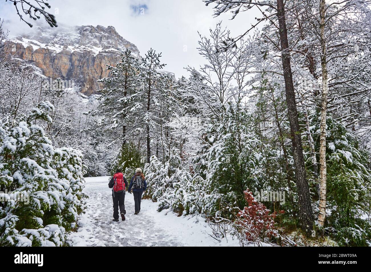 Pyrenees: Two women hiking along snowy path in the National park of Ordesa and Monte Perdido (Huesca province, Aragon region, Spain) Stock Photo