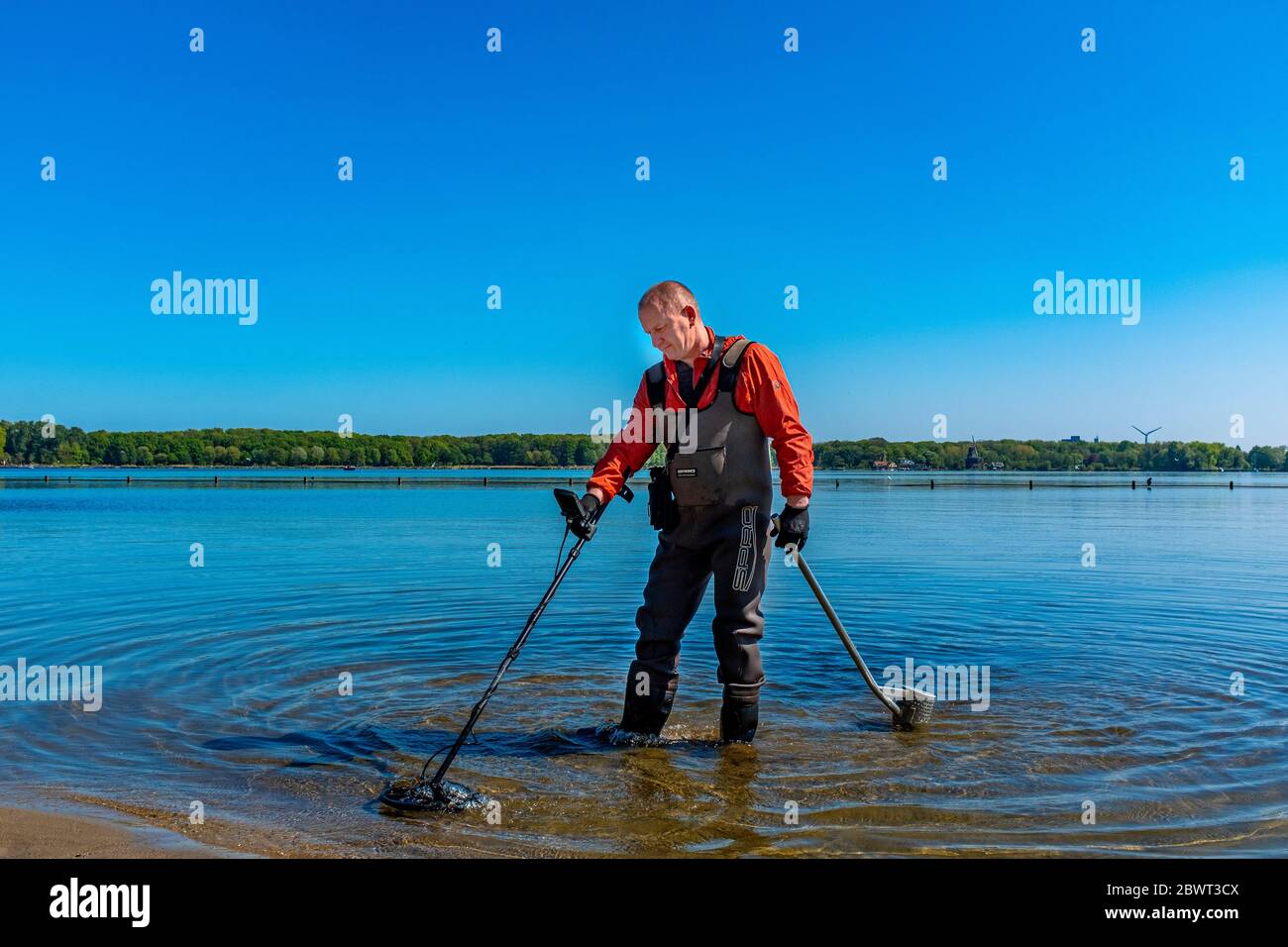 Rotterdam, Netherlands. Man seeking social distance during Corna Crisis by applying his hobby: searching a lake's bed for metals. Stock Photo