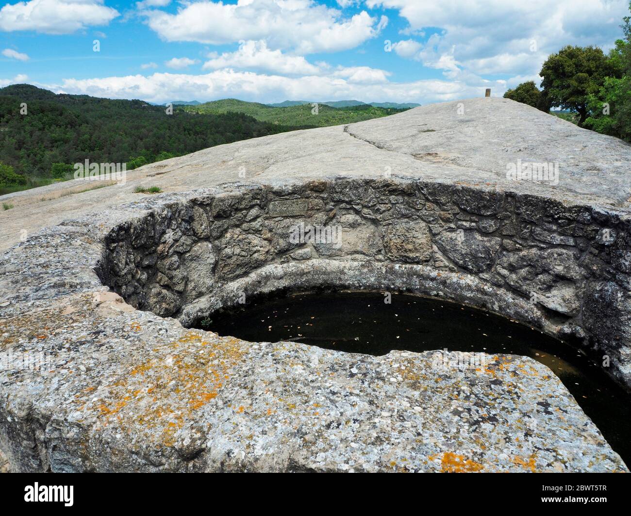 Stone water well, directly carved on the rock. Lluçà village countryside. Lluçanès region, Barcelona province, Catalonia, Spain. Stock Photo