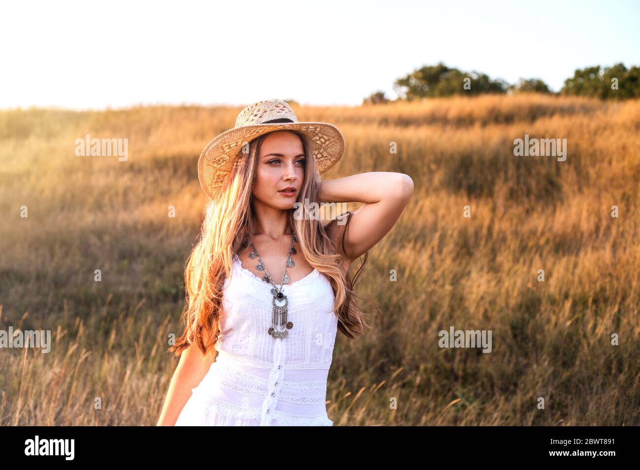 Beautiful woman wearing in white dress and straw hat enjoying nature ...