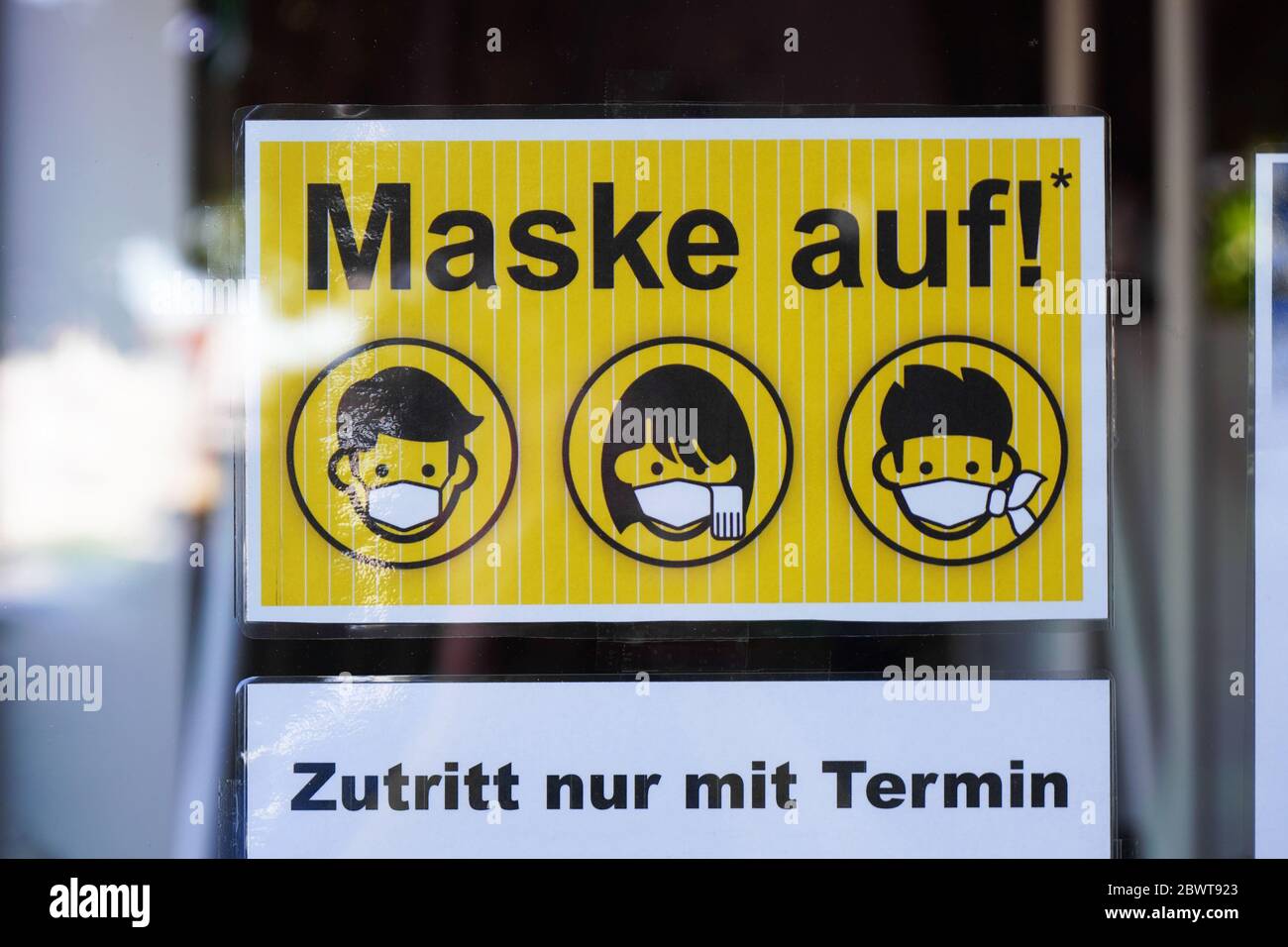 Hannover, Germany - June 1, 2020: German language sign on entrance door to tattoo parlor advises that face mask is mandatory and entry by appointment only. Stock Photo