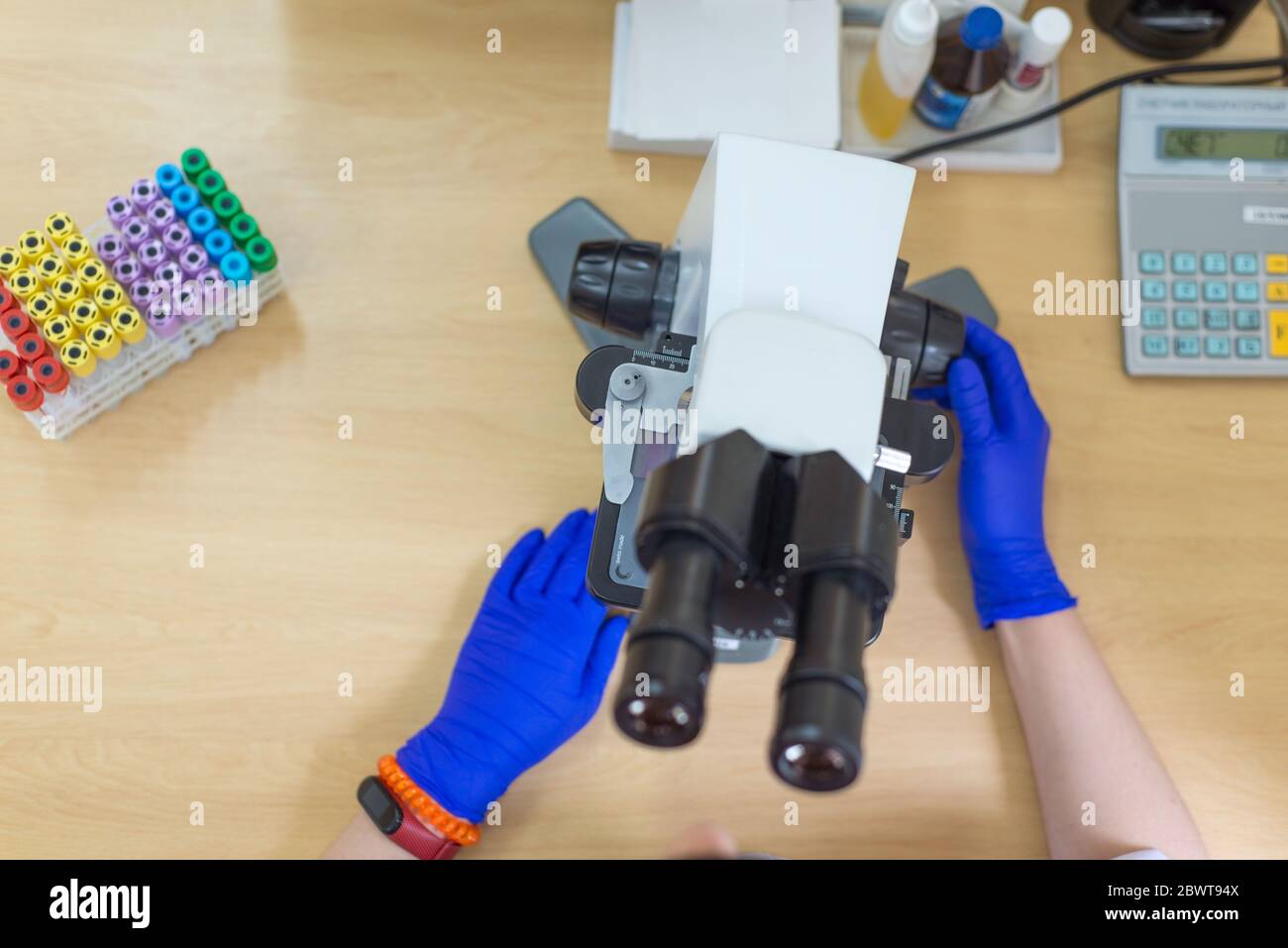 Scientist conducting research taking notes whilst looking through microscope selective focus laboratory assistant is looking through a microscope. Clo Stock Photo