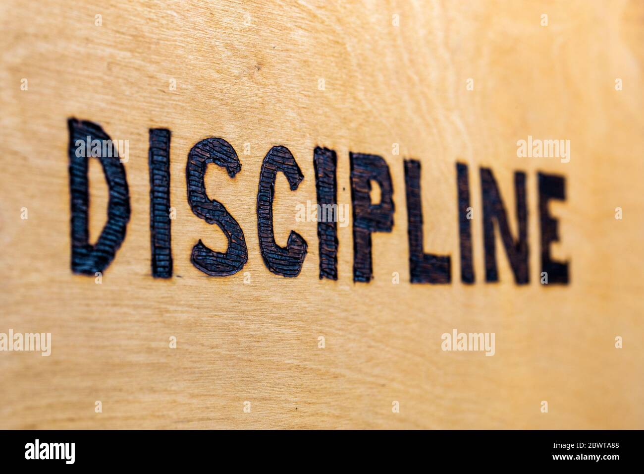 the word discipline burnt on white flat wooden surface - perspective view with selective focus Stock Photo