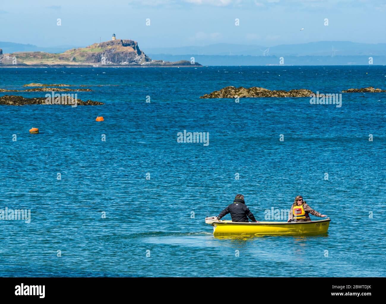 Couple in small boat with outboard engine and view of Fidra Island, North Berwick, East Lothian, Scotland, UK Stock Photo